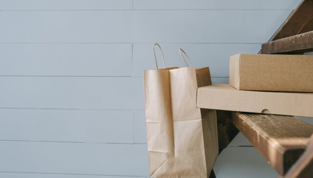 A flat lay of modern eco friendly paper packaging boxes and bags with recycling icons EPR compliance checklist and a laptop showing sustainability analytics dashboard