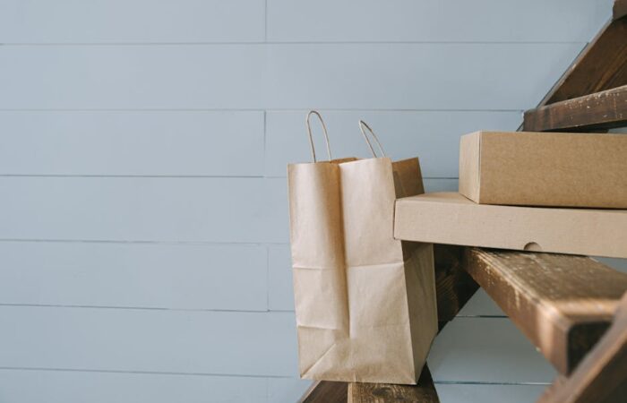 A flat lay of modern eco friendly paper packaging boxes and bags with recycling icons EPR compliance checklist and a laptop showing sustainability analytics dashboard