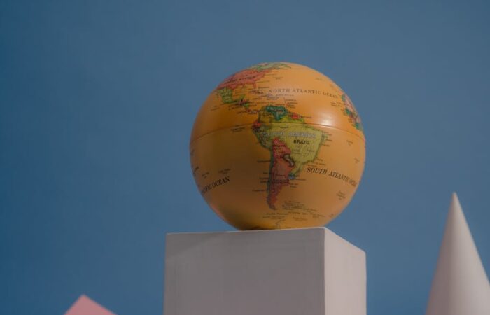 Flat lay comparison of custom printed mailer envelopes and rigid corrugated boxes with international shipping labels on a world map background