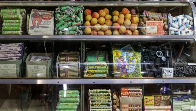Vibrant retro packaging display on a store shelf with s style candy boxes soda bottles and cereal cartons in warm earth tones and bold typography evoking mid century nostalgia