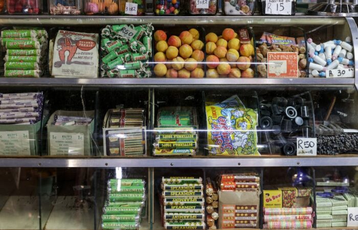 Vibrant retro packaging display on a store shelf with s style candy boxes soda bottles and cereal cartons in warm earth tones and bold typography evoking mid century nostalgia